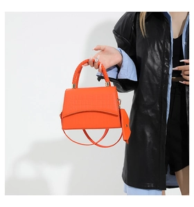 Detail of orange crocodile pattern PU leather handbag with woven handle and shoulder strap