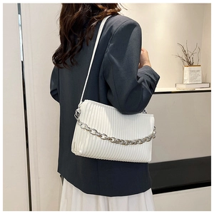 Detail of white pleated shoulder bag with silver chain strap shown on model's shoulder