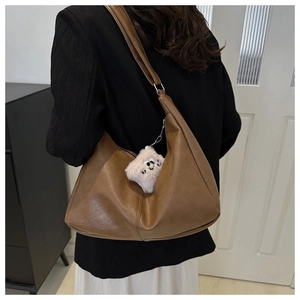 Brown moon-shaped tote bag with textured vintage leather and cute plush monster charm