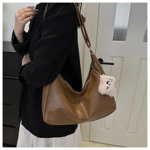 Detail of brown vintage Hobo shoulder bag in PU leather with cute monster plush pendant