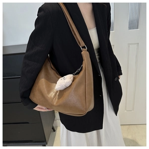 Detailed view of brown PU leather tote bag featuring natural texture and white plush charm