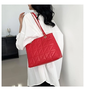 Detail of red quilted tote bag with golden chain strap and glossy faux leather finish