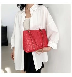 Close-up of red quilted leather tote bag with gold metal chain and leather shoulder straps