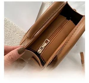 Detail view of the brown leather bag with a smooth metal zipper and internal pocket