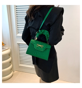 Détail du sac à main vert crocodile avec noeud métallique et poignée plissée élégante