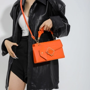 Bright orange quilted crossbody bag with golden geometric clasp and small side pouch