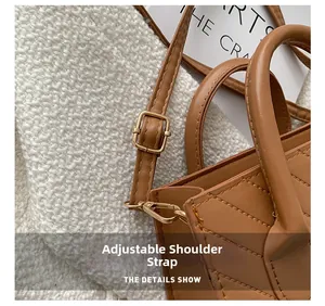 Detail of adjustable shoulder strap with gold metal buckle on brown quilted handbag