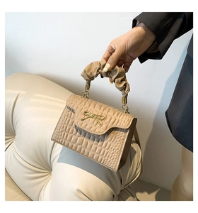 Détail du sac à main kaki à texture crocodile avec nœud doré et poignée nuage souple