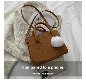 Brown quilted small square crossbody bag shown next to a mobile phone for size comparison