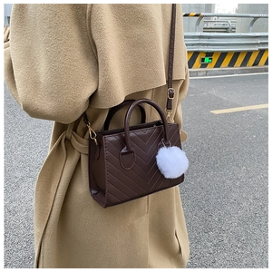 Dettaglio della borsa trapuntata marrone caffè con charm in peluche bianco e hardware dorato