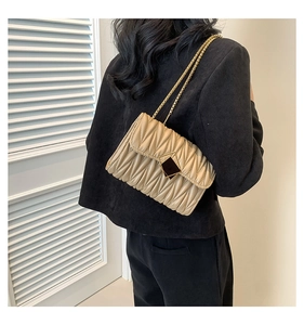 Détail du sac à bandoulière matelassé beige avec chaîne dorée et fermoir métallique chic