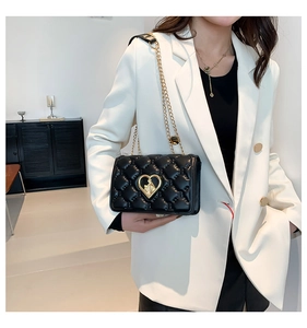 Close-up of black quilted bag with gold heart-shaped lock and metal chain strap