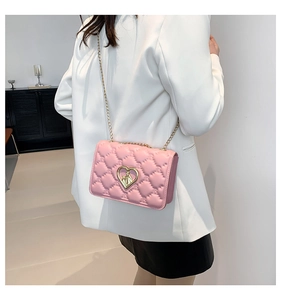 Sac bandoulière rose matelassé avec fermoir cœur et chaîne porté par un mannequin