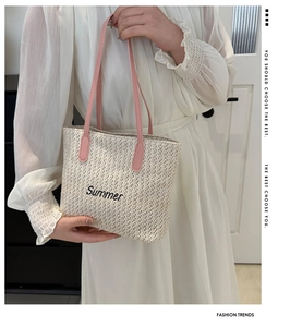 Detail of summer straw tote bag featuring pink handles and black Summer embroidery