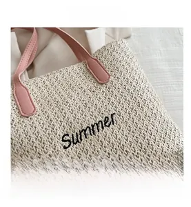 Gros plan du sac en paille tissé avec broderie Summer et poignée en cuir rose