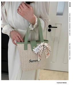 Detail of woven straw tote bag with Summer embroidery and green leather handle with silk scarf