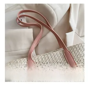 Détail du sac en paille tressée montrant la poignée en cuir rose et les coutures fines