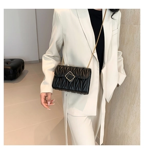 Détail du sac bandoulière matelassé noir avec texture en cuir et boucle métallique dorée