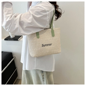 Détail du sac cabas d'été en paille avec broderie noire et anses en cuir vert clair
