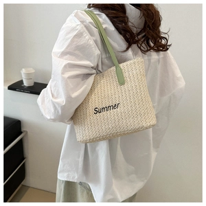 Detail of summer straw tote bag with green handles and Summer embroidery on a model