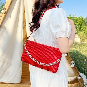 Red pleated chain shoulder bag for women styled in an outdoor minimalist lifestyle setting