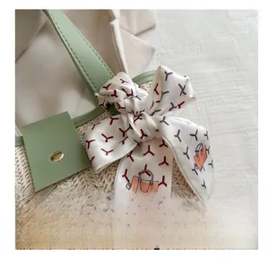 Detail of woven straw bag with green faux leather handle and elegant silk scarf decor