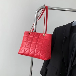 Red quilted chain tote bag with classic rhombus pattern shown hanging on a metal rack