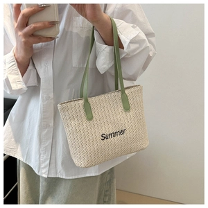 Detail of woven straw tote bag with green leather handles and Summer embroidery