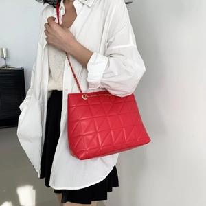 Classic bright red quilted tote bag with gold chain strap worn by a female model