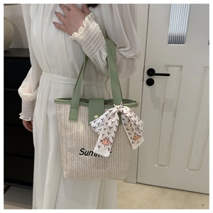 Detail of summer straw tote bag with green leather trim and silk scarf accessory