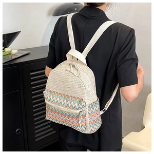 Detail of woven straw backpack showing colorful wave patterns and adjustable straps