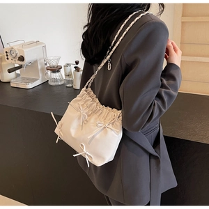Détail du sac nuage plissé crème avec nœuds et bandoulière en chaîne au café