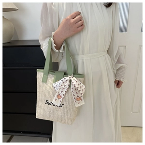 Detail of straw woven tote bag featuring Summer embroidery and decorative silk scarf wrap