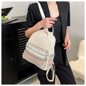 Detail of woven straw backpack with colorful bohemian wave patterns and metal zippers