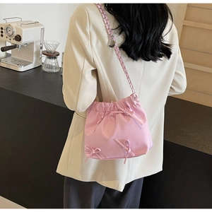 Détail latéral du sac seau rose à cordon avec nœuds 3D décoratifs et bandoulière chaîne