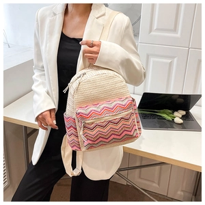 Detail view of a woven straw backpack with colorful zigzag patterns on a female model