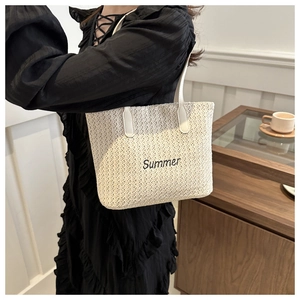 Detail of cream woven tote bag featuring black Summer embroidery and slim white leather strap
