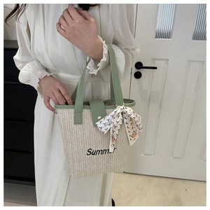 Detail of woven straw tote bag with Summer embroidery, green trim and silk scarf