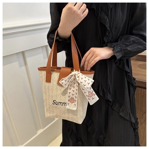 Close-up of woven straw tote with Summer embroidery and colorful decorative silk scarf