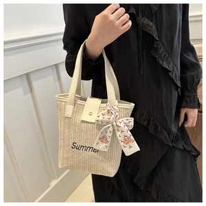 Detail of woven straw tote bag with Summer embroidery and printed silk scarf accessory