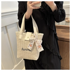 Detail of Summer embroidery on beige woven straw handbag with decorative silk scarf