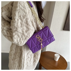 Détail du sac bandoulière en cuir violet matelassé avec chaîne dorée et gland