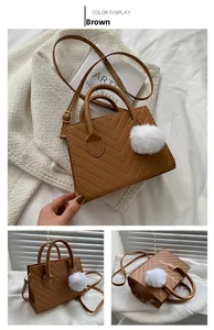 Detail view of brown square bag with V-quilt pattern and white faux fur pompom