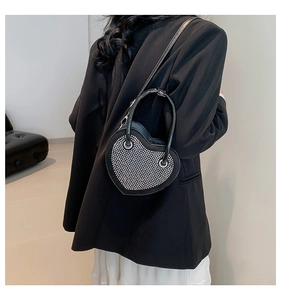 Dettaglio di una borsa nera a forma di cuore con borchie argentate e manico curvo