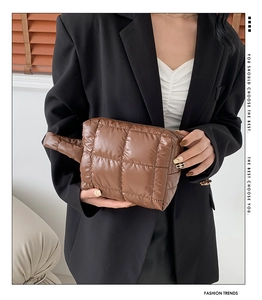 Detail of caramel brown quilted puffer clutch bag with shiny checkered stitching texture
