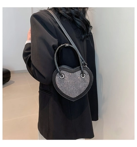 Dettaglio di una borsa nera a forma di cuore con strass argentati e tracolla a catena