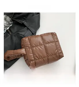 Detail of brown quilted down handbag with glossy nylon finish and square stitching