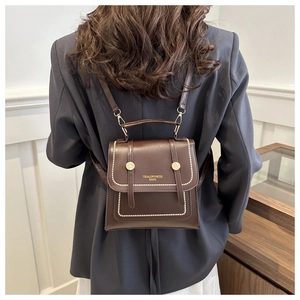 Detail eines dunkelbraunen Lederrucksacks mit Goldnieten und TIDALDRYNESS-Schriftzug