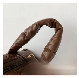Macro detail of brown quilted tote bag showing high-gloss fabric and bronze metal zipper