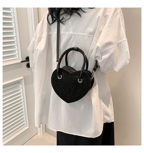 Dettaglio di una borsa nera a forma di cuore con strass e finiture in metallo argentato
